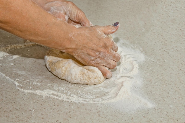 写真 女性の手は,白いキッチンテーブルで粉と面粉を混ぜます.トップビューの焼き付け準備段階の調理