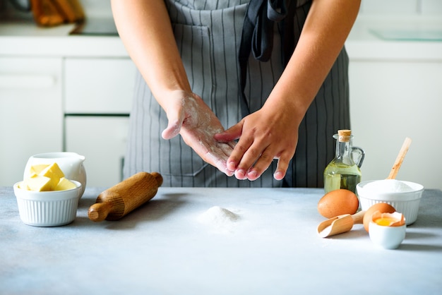 女性の手が生地を練り、背景を焼きます。食材