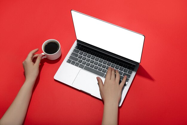 Female hands laptop and coffee on red background