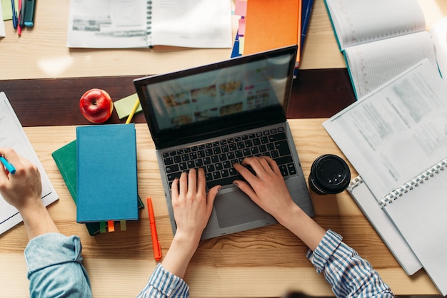 Mani femminili sulla tastiera del laptop, vista dall'alto, concetto di conoscenza. studenti che navigano su internet