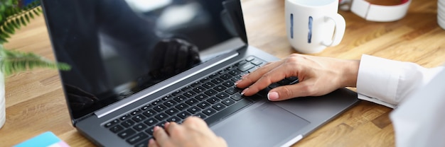 Female hands on laptop keyboard at working table in office