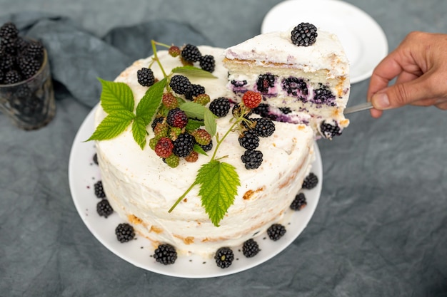 Female hands lays out a piece of homemade cake with blackberries on a saucer.