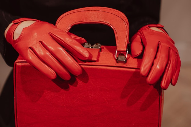 Female hands in a leather gloves holding a classic bright red handbag Fashion shot