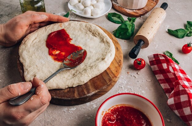 Female hands make pizza the ingredients for homemade margherita pizza on stone surface