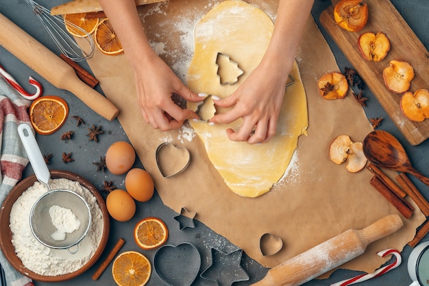 Mani femminili che producono i biscotti dalla pasta fresca a casa