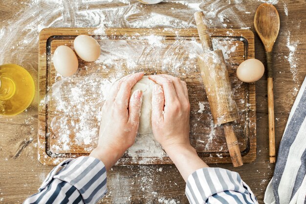 Женские руки, делая тесто на фоне кухни