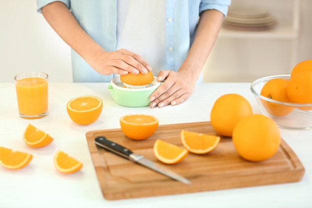 Female hands making orange juice on kitchen