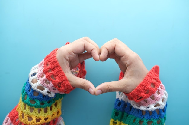 Female hands making sign heart on color background