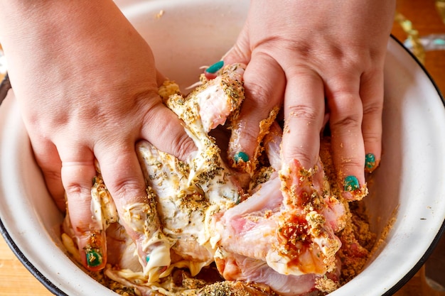 Female hands marinate chicken wings in soy sauce with lemon juice and herbs