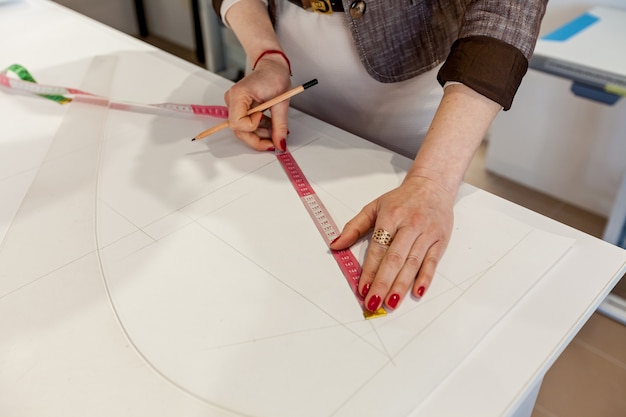 Female hands marking out a pattern on a white table