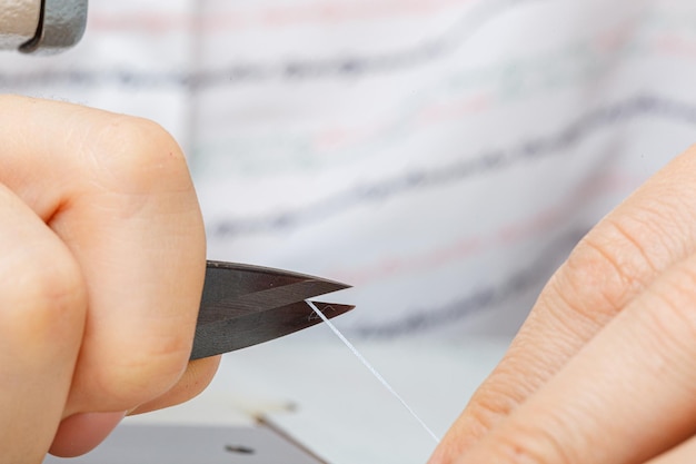 Female hands of a master tailor cuts a thread with scissors