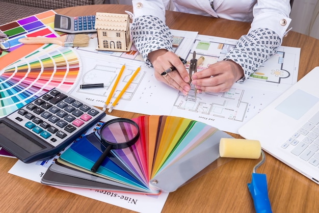 Female hands measuring on house plan in office