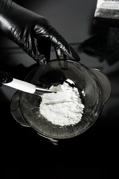 Female hands in medical gloves hold a bowl of white powder