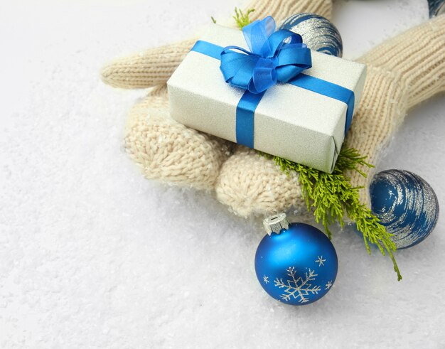 Photo female hands  in mittens with gift box, on white background