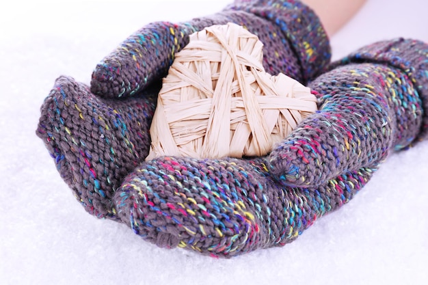 Photo female hands in mittens with heart on snow background