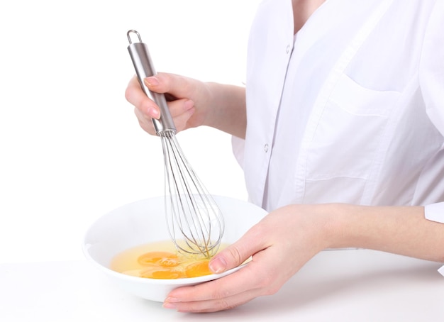 Female hands Mixing eggs in bowl isolated on white