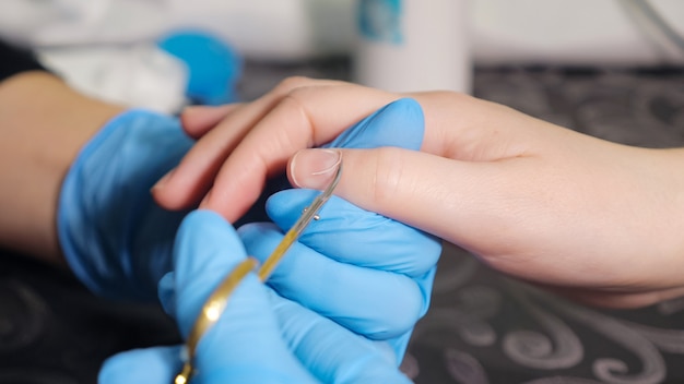 female hands in nail salon receiving a manicure by a beautician, close-up