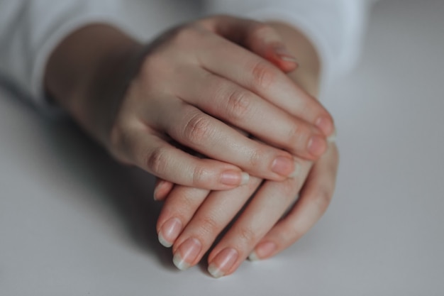 Female hands. One hand rests on the other on a white