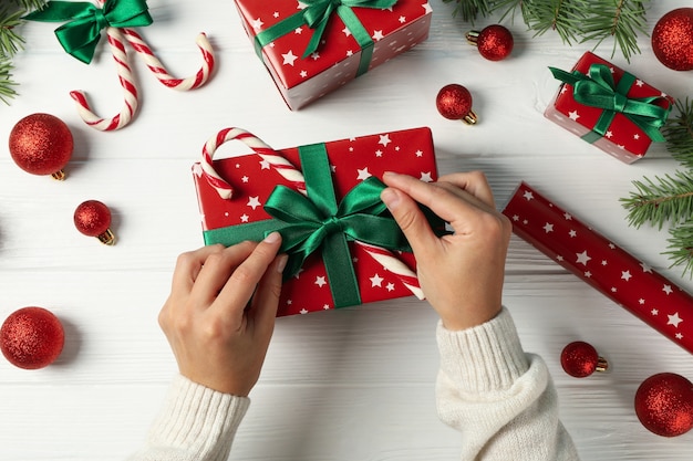 Female hands open the box on white wooden table with Christmas accessories