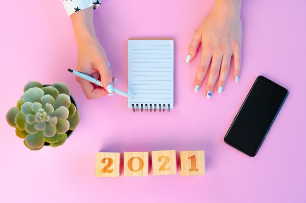 Female hands and open notepad on pink background