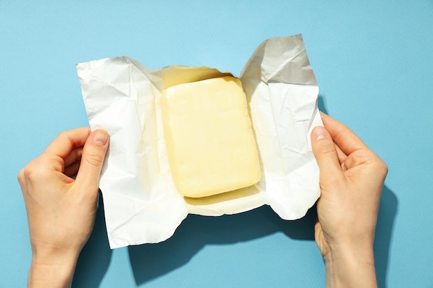 女性の手が青の背景にバターでパッケージを開く