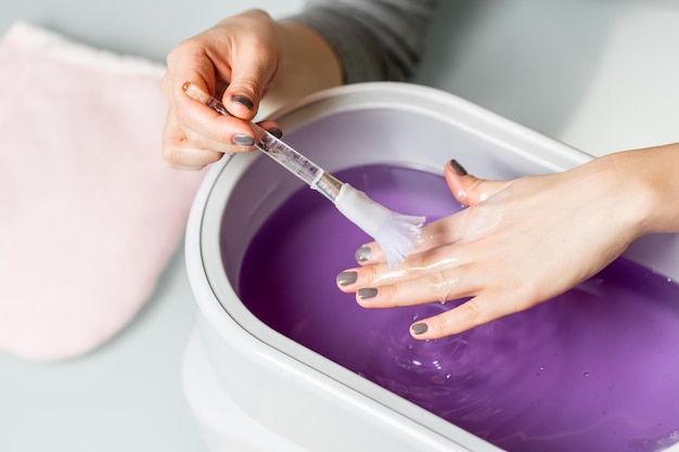 Photo female hands in a paraffin wax bowl