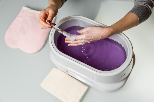 Female hands in a paraffin wax bowl