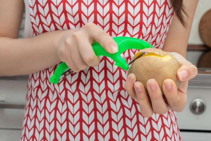 Photo female hands peel potatoes with a peeler