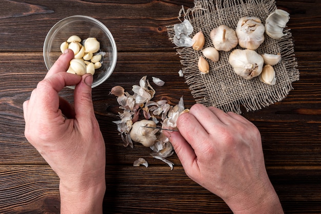 Female hands peeling garlic on a wooden table