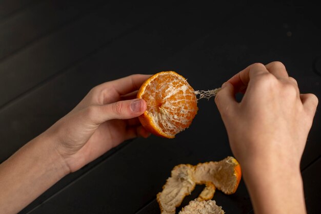 female hands peeling a tangerine over the table