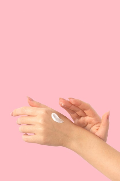 Female hands on a pink background smear cream long beige nails manicure and gel polish