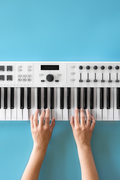 Female hands play musical keys on a blue background top view