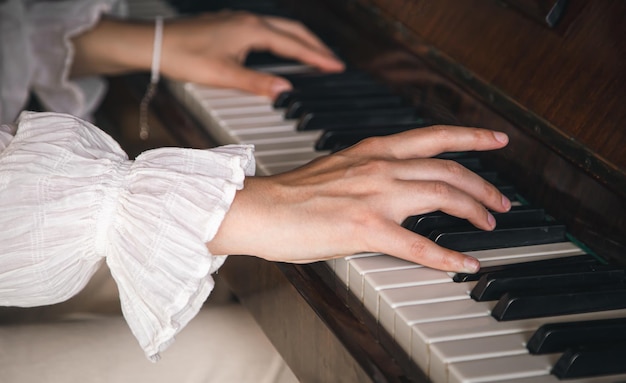 Mani femminili che giocano il vecchio primo piano del pianoforte