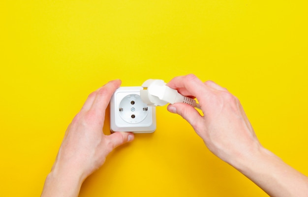 Female hands plug in power plug into electro outlet. minimalism. top view