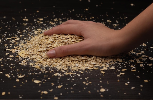 Female hands pouring muesli on a black background