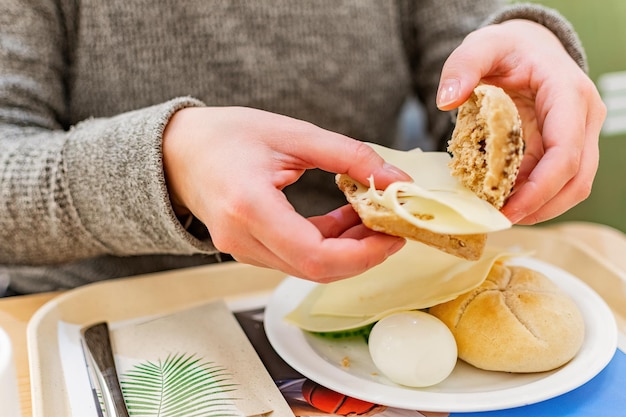 サンドイッチの朝食を準備する女性の手