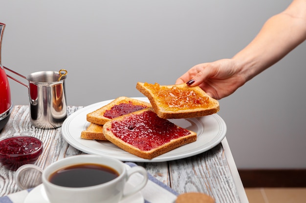 Female hands preparing toasts with fruit jam