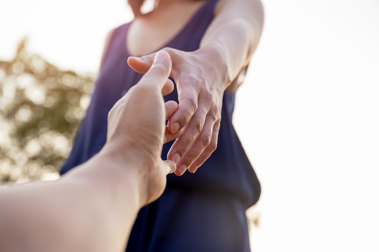 女性の手がお互いに助けを求めて手を差し伸べる。