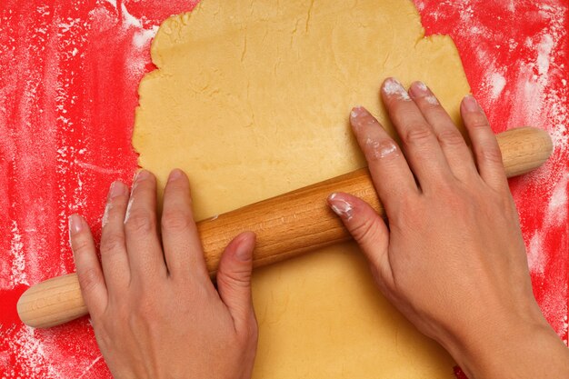 Female hands roll out the dough for Christmas cookies