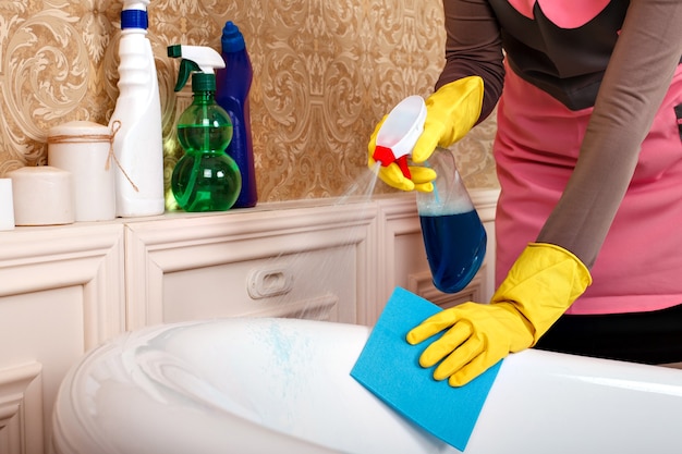 Female hands in rubber gloves cleans bathroom.