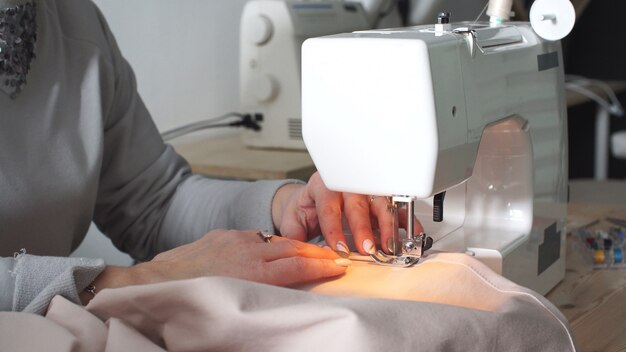 Female hands of a seamstress close-up sewing cotton with a sewing machine