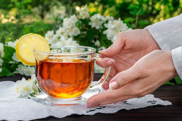 Female hands serve a glass cup with tea lemon embroidered napkin