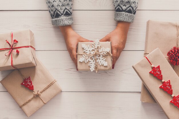 Female hands show christmas holiday handmade present in craft paper with rope