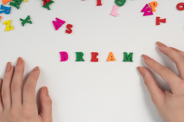 Female hands spread the word dream from colored letters