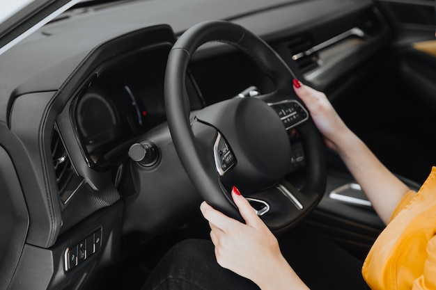 Female hands on the steering wheel of a car while driving