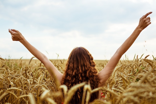 Female hands stick out from the wheat field happy young woman is free in a ripe golden wheat field n...