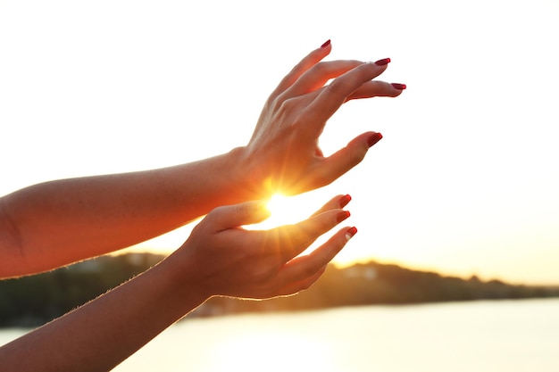 Female hands on sunny sky background