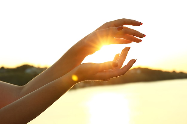 Female hands on sunny sky background