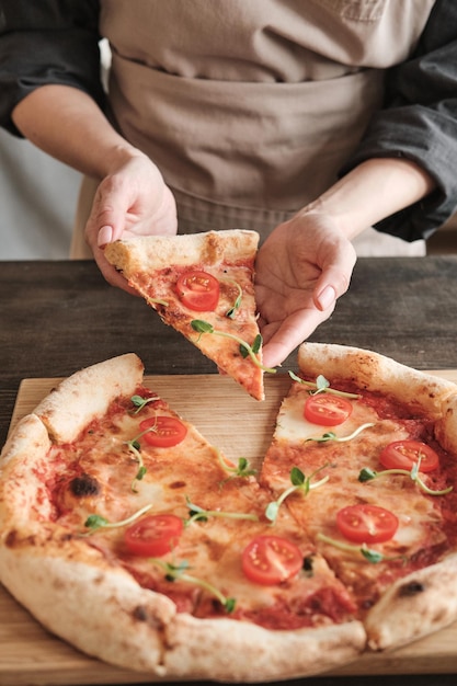 Female hands taking hot pizza slice