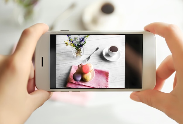 Photo female hands taking photo of macaroons and cup of coffee